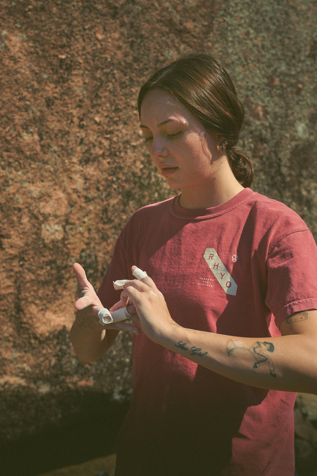 Person in a Rhyo / 02: Process t-shirt wrapping their fingers in tape before rock climbing.