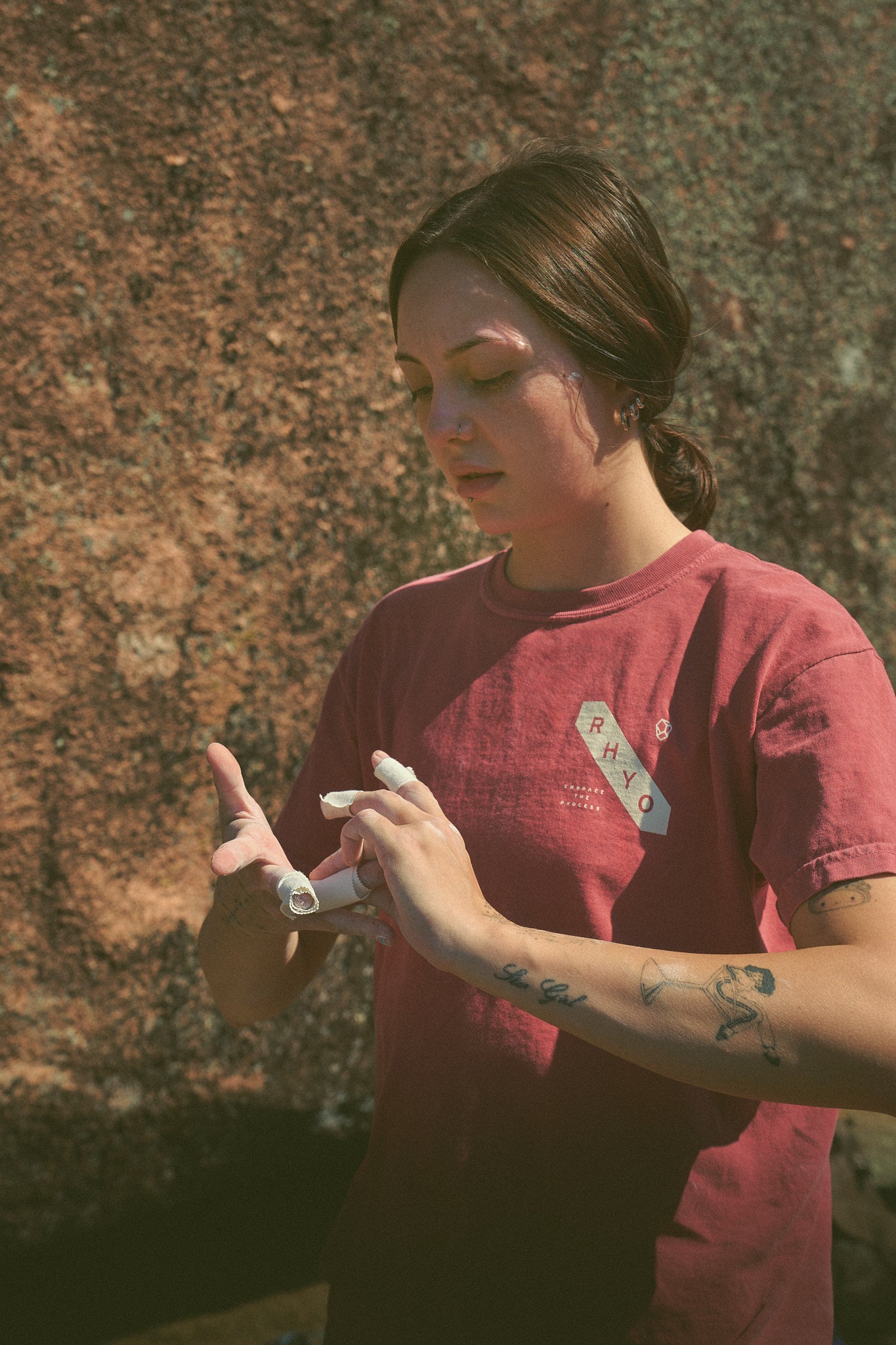 Person in a Rhyo / 02: Process t-shirt wrapping their fingers in tape before rock climbing.