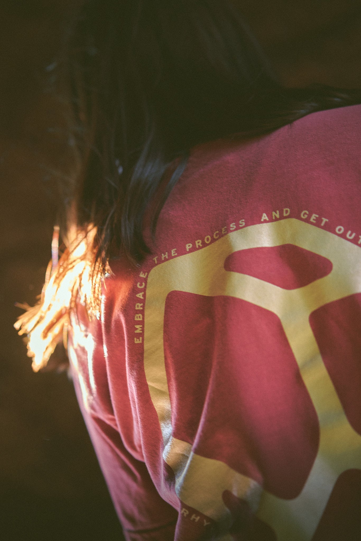 Back of a person wearing the Rhyo / 02: Process t-shirt with a logo and text.