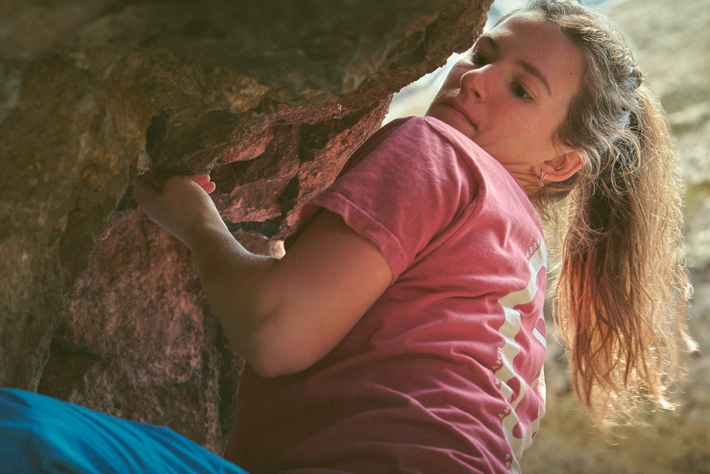Person climbing a rock face wearing the Rhyo / 02: Process t-shirt.