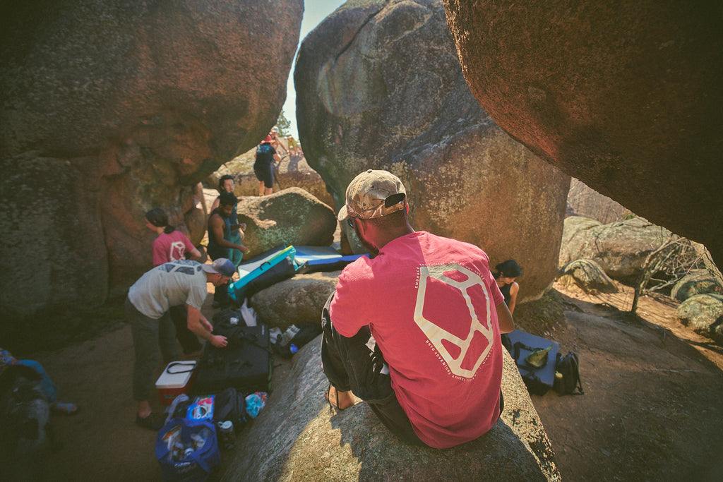 Group of people wearing Rhyo Apparel preparing for a bouldering session among large rocks.