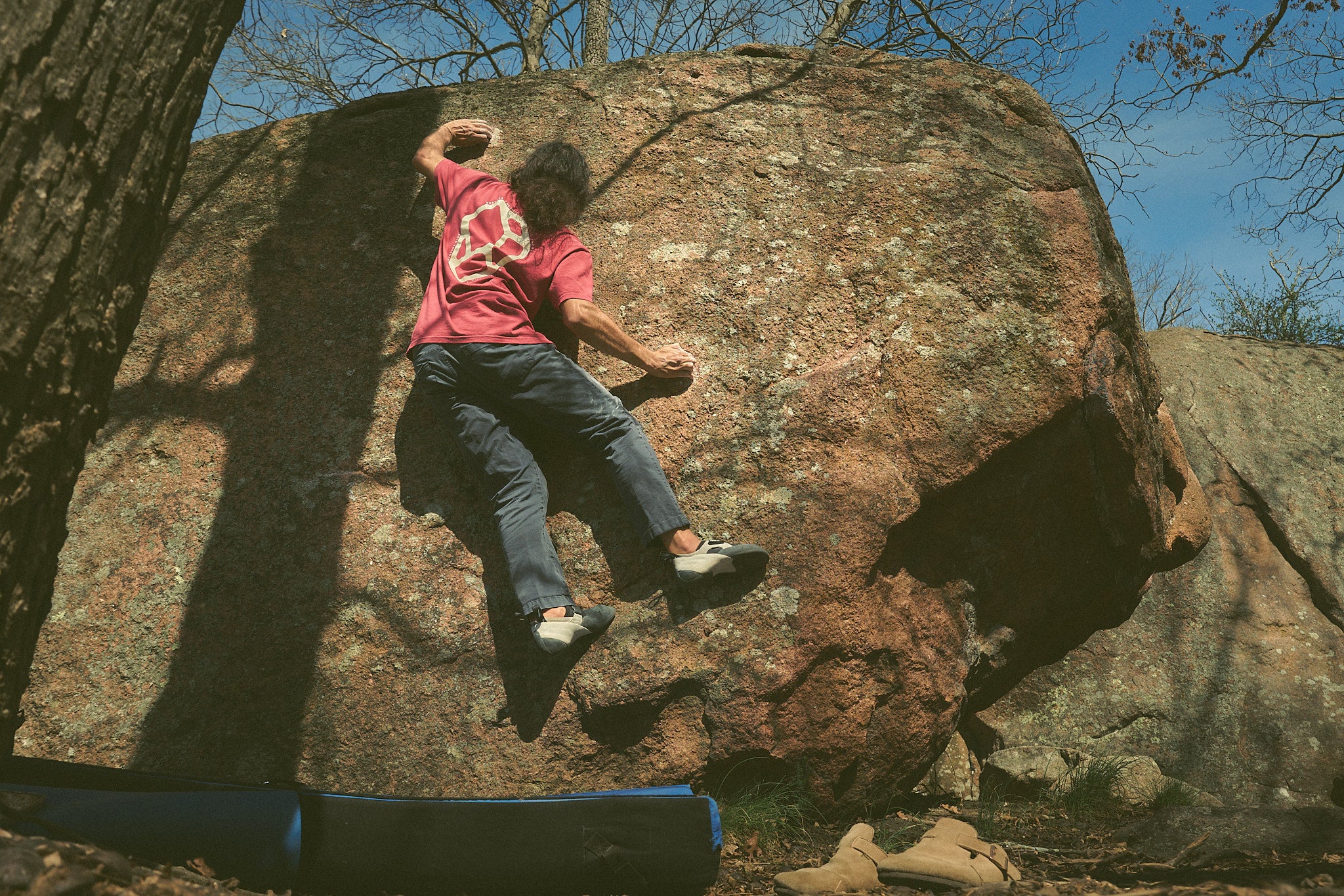 Person climbing a large rock wearing the Rhyo / 02: Process t-shirt.