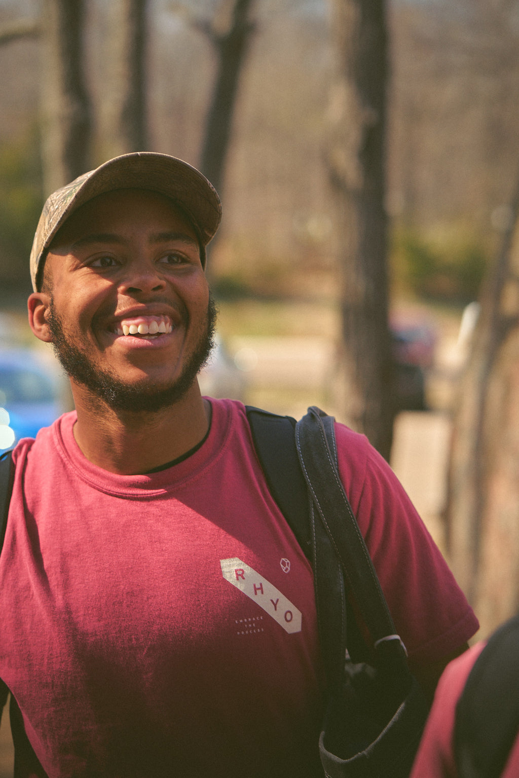 Man wearing the Rhyo /02: Process t-shirt, smiling outdoors.
